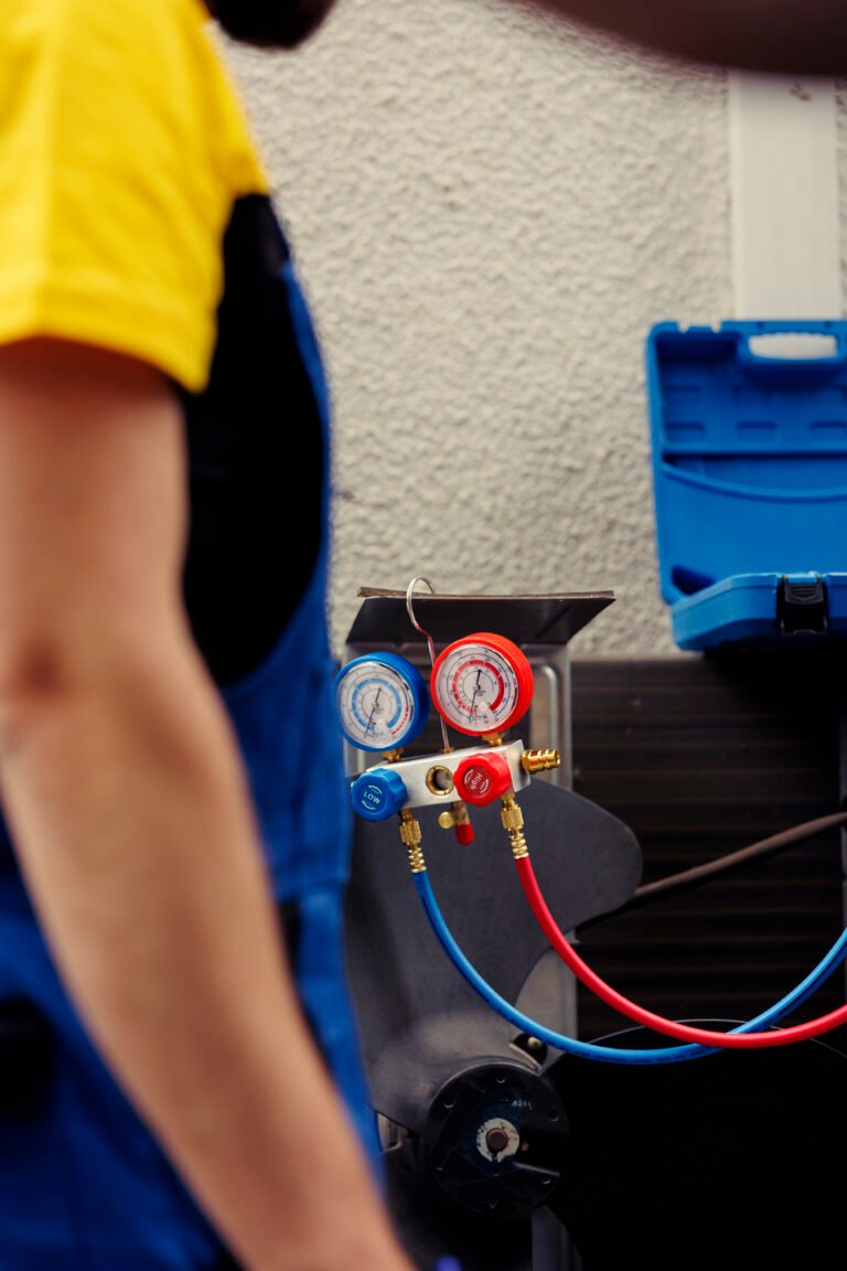 Adept repairman hired to check outdoor hvac system refrigerant tank in need of maintenance, using manometers. Licensed serviceman with ac gauges vacuum pump looking at air conditioner freon levels